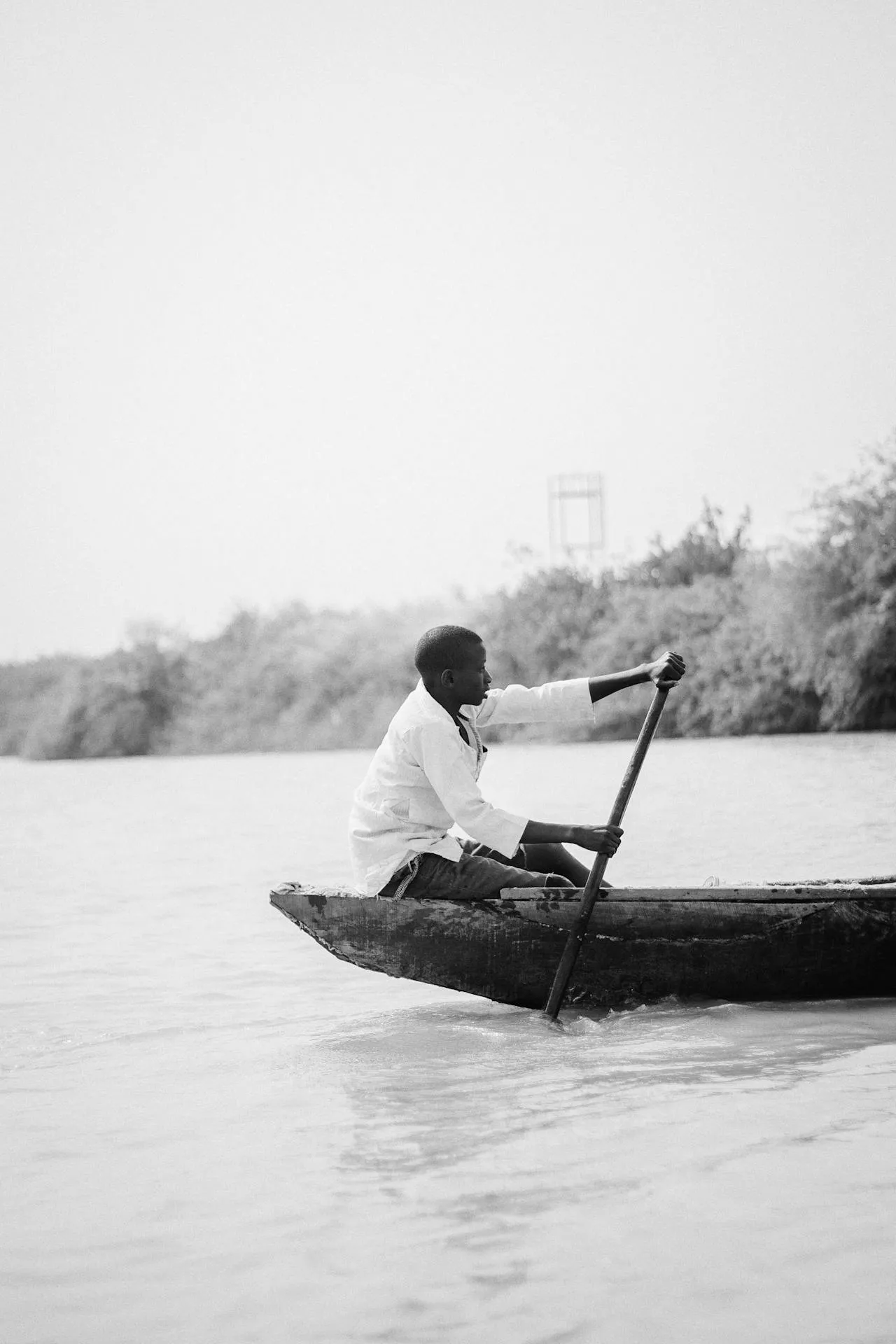 Solo traveller paddling a wooden canoe across a calm Malawian waterway